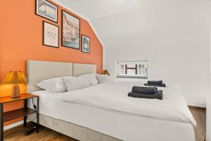 a bedroom with a white bed with an orange wall at LUMEN - Design Loft - Zentral - PS5 - Balkon in Rotenburg an der Fulda