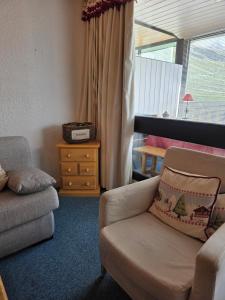 a living room with a couch and a chair at Le Serac Panoramic Mountain View spacious 40m2 managed by private host in Val Thorens +20 photos