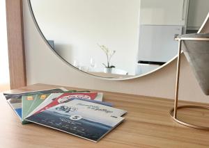 a stack of magazines on a table with a mirror at Apartamento Son do Mar in Porto do Son