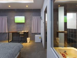 88 Fine Hotel @ Suratthani Airport في سوراثاني: حمام مع حوض استحمام وتلفزيون على الحائط