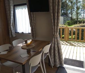 Una mesa de madera con sillas blancas y un porche. en New mobile home near Touquet-Paris-Plage, en Étaples