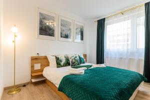 a bedroom with a bed with a green blanket at Mountain Views Urban Plaza in Braşov