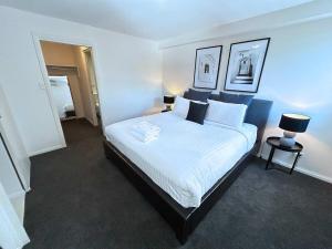 een slaapkamer met een bed met witte lakens en kussens bij Bribie Sunset Vistas in Bongaree