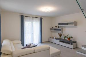a living room with a white couch and a large window at Villa Katalea - piscina privata e barbecue in Asti