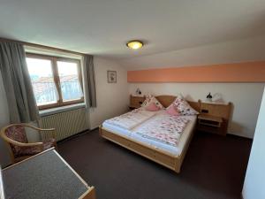 a bedroom with a bed and a desk and a window at Gästehaus-Pension Keiss in Hopferau