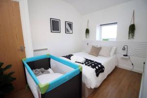 a bedroom with a bed and a baby crib at Rustic Elegant Retreat Opposite Stadium in Cardiff