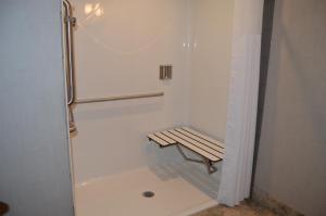 a bathroom with a bench next to a shower at Cobble Creek Lodge in Maple Creek