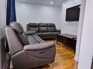 a living room with a couch and a flat screen tv at Barnsley cozy home in Little Houghton