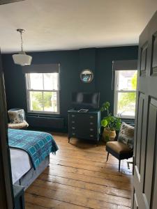 a bedroom with a bed and a desk and two windows at Efail Y Garn in Swansea