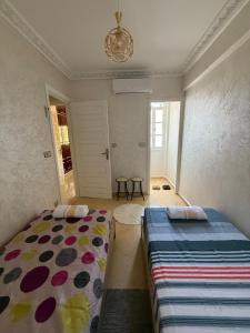 a bedroom with two beds and a chandelier at Appartement Aeropuerto in Marrakesh