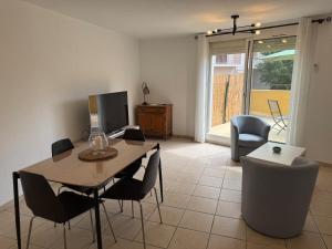a living room with a table and chairs and a television at Le Sudiste in La Ciotat