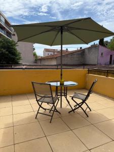 a table and two chairs with an umbrella on a roof at Le Sudiste in La Ciotat