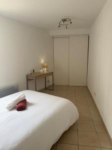 a bedroom with a white bed with a red pillow on it at Le Sudiste in La Ciotat