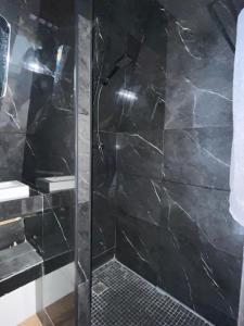 a shower in a bathroom with black marble at le moodeng in Villampuy +20 photos