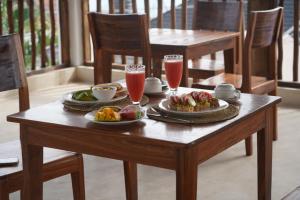 a wooden table with two plates of food and drinks at Tumbili Hotel Boutique in Paje