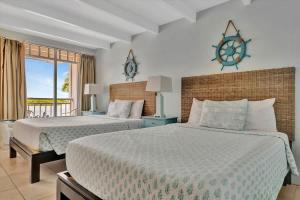 ラスキンにあるBahia Waterview Suite Pool Tennis Beach Fishingのベッドが2つあり、壁に時計がある寝室