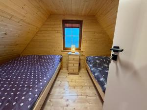 a small room with two beds and a window at Bociani Zakątek nad jeziorem in Leszczewo