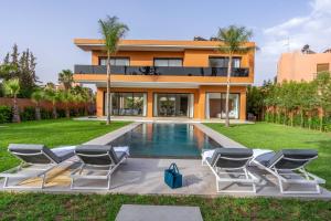 a house with a swimming pool and chairs in front of it at Villa Mareva & Spa Marrakech in Marrakesh