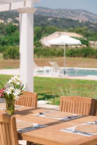 een houten tafel met een vaas met bloemen erop bij Villa Botanica in Kassiopi