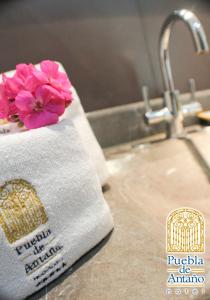 a towel with a pink flower on a sink at Hotel Puebla de Antaño in Puebla