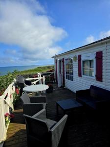 una casa con terraza con mesa y sillas en Mobil-Home Vue Mer 4 personnes, en Saint-Cast-le-Guildo