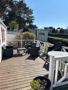 una terraza de madera con sillas y mesas. en Mobil-Home Vue Mer 4 personnes, en Saint-Cast-le-Guildo