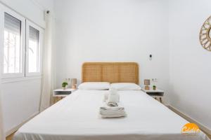 a white bedroom with a large bed with white sheets at Garcia Rooms by Cadiz Time in Cádiz