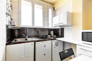 une cuisine avec des armoires blanches et un évier dans l'établissement Studio Rue Nationale, à Paris