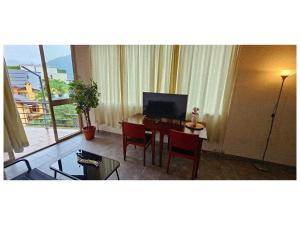 a room with a desk with a television and a table with chairs at Apartment with two rooms and shared bathroom in Minusio