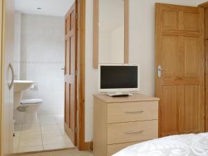 a bedroom with a television on a dresser with a bathroom at Mickle Hill Mews in Gargrave