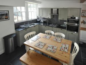 a kitchen with a wooden table and white chairs at Cornerstones in Ambleside