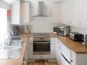 une cuisine avec des armoires blanches et un évier dans l'établissement Bluebell Cottage, à Nether Stowey