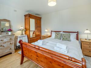 a bedroom with a wooden bed with towels on it at The Coach House in Aldington