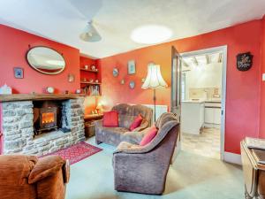 ein Wohnzimmer mit roten Wänden und einem Kamin aus Stein in der Unterkunft Old Orchard Cottage in Dilton