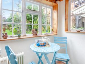 einen blauen Tisch und Stühle in einem Zimmer mit Fenstern in der Unterkunft Old Orchard Cottage in Dilton