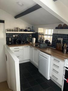a kitchen with white cabinets and a white dishwasher at Watchmaker Cottage in Bellingham