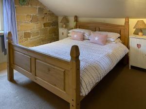 a bedroom with a wooden bed with pink pillows at Finkle Barn in Fryup