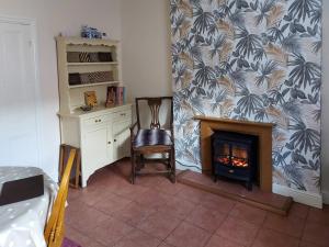 a room with a fireplace with a desk and a chair at Squirrel Cottage in Thornton Dale