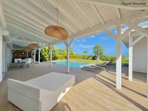 a patio with a white couch and a pool at Villa Cokoon in Saint-François