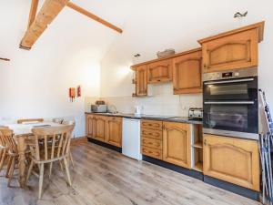 a kitchen with wooden cabinets and a table and chairs at Leedale Cottage in Saltmarshe +11 photos