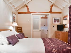 ein Schlafzimmer mit einem großen weißen Bett mit lila Kissen in der Unterkunft Ash Garth Cottage in Kirby Misperton