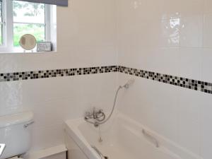 ein weißes Badezimmer mit Badewanne und Toilette in der Unterkunft Foxglove Cottage in Wootton Fitzpaine + 2 Fotos