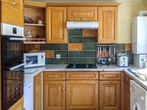 a kitchen with wooden cabinets and a stove top oven at Kay's Cottage in Buckfastleigh