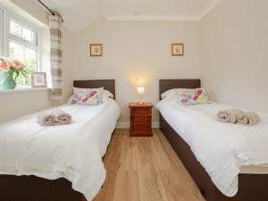 two twin beds in a room with a wooden floor at 1 Luckington Stables-W8321 in Holcombe