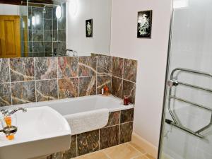 une salle de bain avec une baignoire et un lavabo dans l'établissement Penno Cottage - 24440, à Bodmin