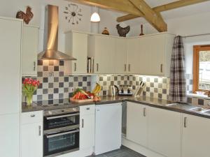 a kitchen with white cabinets and black and white tiles at The Stables in Bodmin