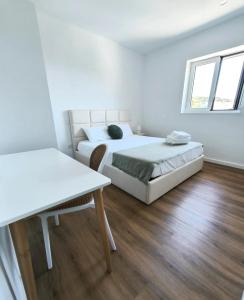 a white bedroom with a bed and a table at Loreto Apartment in Bragança