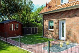 a house with a fence in front of a yard at Nr 19 - Ferienhaus "Florentina" in Carolinensiel