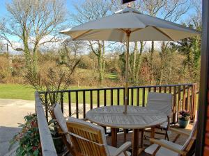 a table and chairs with an umbrella on a porch at Rosewater Lodge in Saint Teath