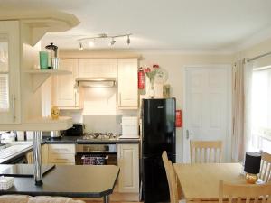 a kitchen with a black refrigerator and a table at Rosewater Lodge in Saint Teath
